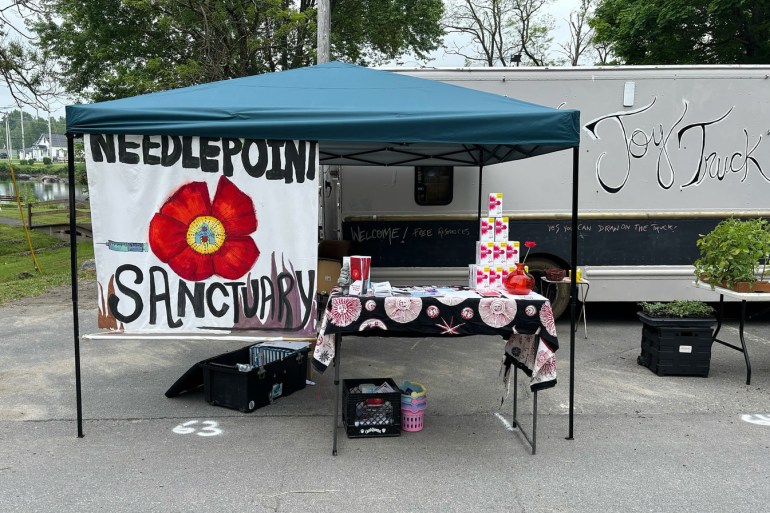 A photo of a table set up by Needlepoint Sanctuary under a tent outside.